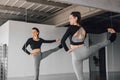 Beautiful female Yoga Coach practicing in front of the mirror of a fitness Pilates center