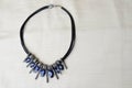 A beautiful, feminine, fashionable necklace on a black rubber band with blue shining gems, diamonds against a beige fabric backgro Royalty Free Stock Photo