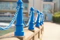Beautiful fencing of sidewalk in form of posts with blue iron chains