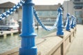 Beautiful fencing of sidewalk in form of posts with blue iron chains