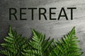 Beautiful fern leaves and word Retreat on grey stone background, flat lay
