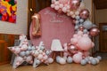 Beautiful festive decorations, pink and grey balloons arch, wooden stars, white chair and number one balloon on wooden round