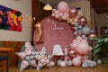 Beautiful festive decorations, pink and grey balloons arch, wooden stars, white chair and number one balloon on wooden round