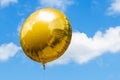 Beautiful festive gold balloon on blue sky and clouds background Royalty Free Stock Photo