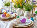 Beautiful festive table setting with colorful Easter eggs and decorative dishes and flowers Royalty Free Stock Photo