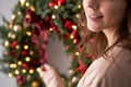 Beautiful festive wreath of fresh spruce in woman hands. Xmas circlet with red and gold ornaments and balls. Christmas Royalty Free Stock Photo