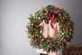 Beautiful festive wreath of fresh spruce in woman hands. Xmas circlet with red and gold ornaments and balls. Christmas Royalty Free Stock Photo