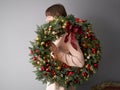 Beautiful festive wreath of fresh spruce in woman hands. Xmas circlet with red and gold ornaments and balls. Christmas Royalty Free Stock Photo