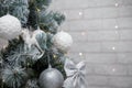 Beautiful fir tree decorated with white baubles and silver bows on brick wall with golden garland lights bokeh. Merry Christmas. Royalty Free Stock Photo