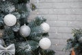 Beautiful fir tree decorated with white baubles and silver bows on brick wall with golden garland lights bokeh. Merry Christmas. Royalty Free Stock Photo