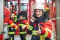 Beautiful fire fighter woman with her helmet standing in the firehouse Royalty Free Stock Photo