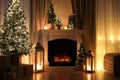Beautiful fireplace, Christmas tree and other decorations in living room at night. Interior design Royalty Free Stock Photo