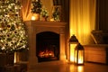 Beautiful fireplace, Christmas tree and other decorations in living room at night. Interior design Royalty Free Stock Photo