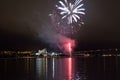 Beautiful firework on night sky in tromsoe city with bridge, cathedral and colorful reflection on the cold fjord Royalty Free Stock Photo