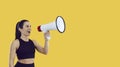 Sporty woman with megaphone making sale announcement on yellow copy space background