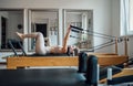 Beautiful fit-shape female dressed sporty doing strength exercises using pilates reformer machine in a sport athletic gym. Active