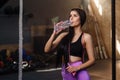 Beautiful fit woman drinking water from plastic bottle after workout in the gym. Royalty Free Stock Photo