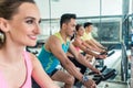 Beautiful fit woman smiling during workout at indoor cycling group class