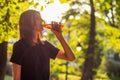 Beautiful fitness athlete woman are drinking iced tea after workout exercising on sunset evening in park. Royalty Free Stock Photo