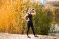 Beautiful fitness athlete woman drinking water after work out exercising on autumn park Royalty Free Stock Photo