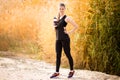 Beautiful fitness athlete woman drinking water after work out exercising on autumn park Royalty Free Stock Photo