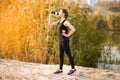 Beautiful fitness athlete woman drinking water after work out exercising on autumn park Royalty Free Stock Photo