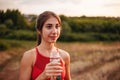 Beautiful fitness athlete woman drinking water after work out exercising on sunset evening summer in park outdoors Royalty Free Stock Photo