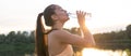 Beautiful fitness athlete woman drinking water after workout exercising on sunset evening summer in beach outdoor Royalty Free Stock Photo