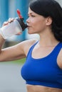 Beautiful fitness athlete woman resting drinking water after work out exercising on beach summer evening in sunny sunshine outdoor Royalty Free Stock Photo