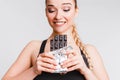 Beautiful fitness girl on a light gray background with chocolate. The concept of dealing with the desire to eat junk