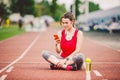 Beautiful fitness girl uses smartphone at stadium after workout. Sports and healthy. Sport woman use of cellphone inside sport Royalty Free Stock Photo