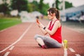 Beautiful fitness girl uses smartphone at stadium after workout. Sports and healthy. Sport woman use of cellphone inside sport Royalty Free Stock Photo