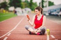 Beautiful fitness girl uses smartphone at stadium after workout. Sports and healthy. Sport woman use of cellphone inside sport Royalty Free Stock Photo