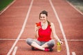 Beautiful fitness girl uses smartphone at stadium after workout. Sports and healthy. Sport woman use of cellphone inside sport Royalty Free Stock Photo