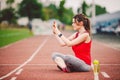 Beautiful fitness girl uses smartphone at stadium after workout. Sports and healthy. Sport woman use of cellphone inside sport Royalty Free Stock Photo