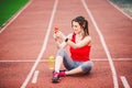 Beautiful fitness girl uses smartphone at stadium after workout. Sports and healthy. Sport woman use of cellphone inside sport Royalty Free Stock Photo