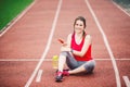 Beautiful fitness girl uses smartphone at stadium after workout. Sports and healthy. Sport woman use of cellphone inside sport Royalty Free Stock Photo