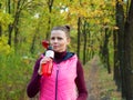 Beautiful fitness sport girl in autumn park in sportswear drinks water or isotonic drink from a sports bottle. Royalty Free Stock Photo