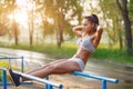 Beautiful fitness woman doing exercise on bars sunny outdoor