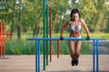 Beautiful fitness woman doing exercise on parallel bars sunny outdoor