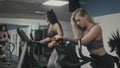 Beautiful fitness women doing exercises on ellipsoid and bike in gym in slomo