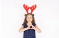 A beautiful five-year-old girl in Christmas reindeer antlers and a New Year`s dress with sequins poses Royalty Free Stock Photo