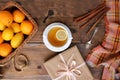 Beautiful flat on an old wooden background, a cup of tea with lemon and cinnamon sticks, candles, a gift in paper, cones, top view Royalty Free Stock Photo
