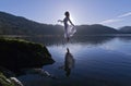 Beautiful Floating Girl dressed in white, silhouetted by the sun reflected in still lake