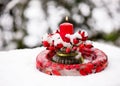 Floristic arrangement with rose hip branches, frozen wreath made of ice, red rose hips berries and burning red candle in snow. Royalty Free Stock Photo