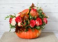 Beautiful flower arrangement in a pumpkin. Autumn floral pumpkin background. Pumpkin with flowers on a wooden background. Royalty Free Stock Photo