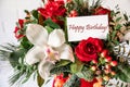 Beautiful flower arrangement of white orchid, red roses, natural spruce branches with card text Happy Birthday