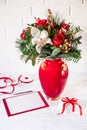 Beautiful flower arrangement of white orchid, red roses, natural spruce branches in red vase next to empty greeting card for text Royalty Free Stock Photo