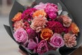 Beautiful flower bouquet with roses, cloves in hands. Florist. Flower shop Pink and orange flowers.