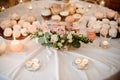 Beautiful flower composition and candles decorating a festive table served with cakes Royalty Free Stock Photo